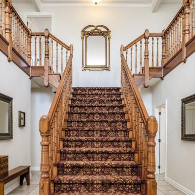 Big Wooden Staircase With Vintage Carpet Inside Apartment With White Walls
